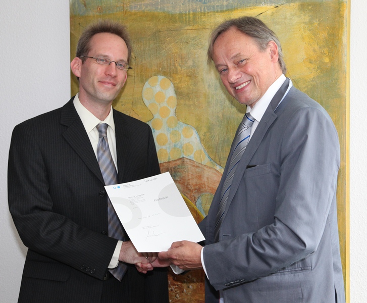 Hochschulpräsident Prof. Dr. Hartmut Ihne (rechts) überreichte Dr. Dirk Reith die Ernennungsurkunde zum Professor.